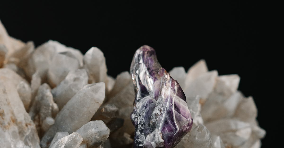 An elegant amethyst crystal on a quartz cluster against a black backdrop.